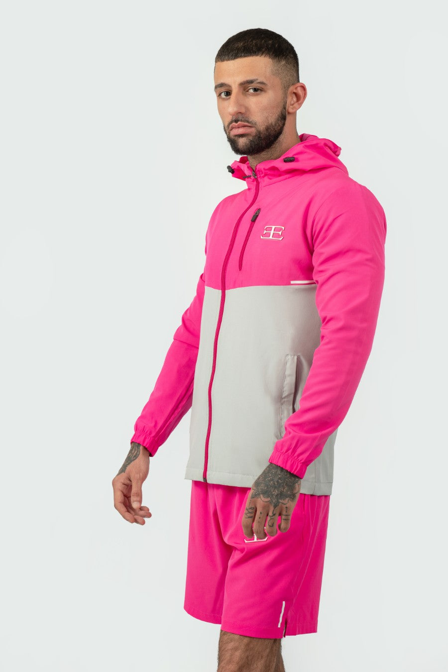 man wearing pink and grey tracksuit jacket with pink shorts with a elegante logo on a white background