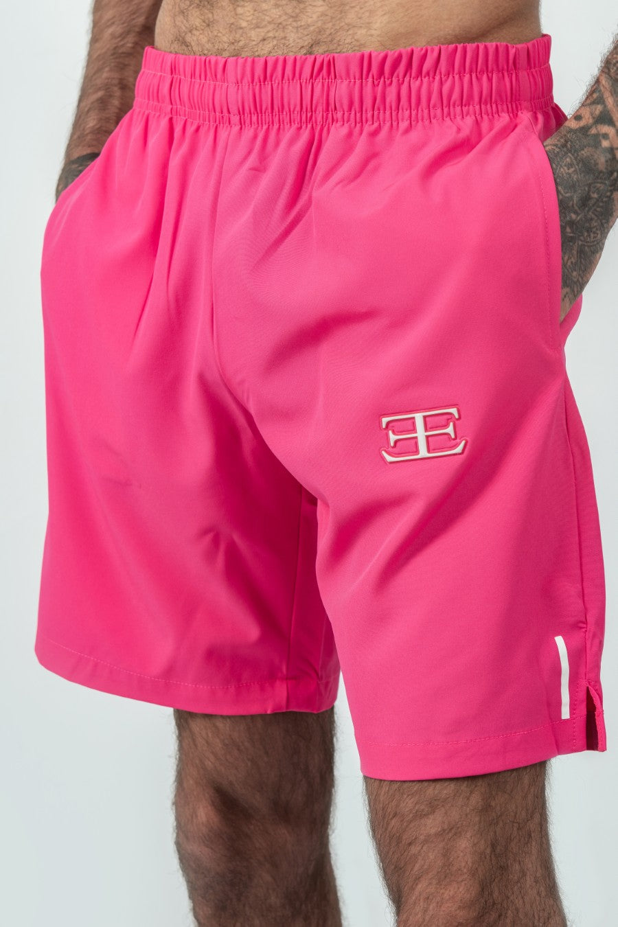 man wearing pink shorts and pockets with a elegante logo on a white background