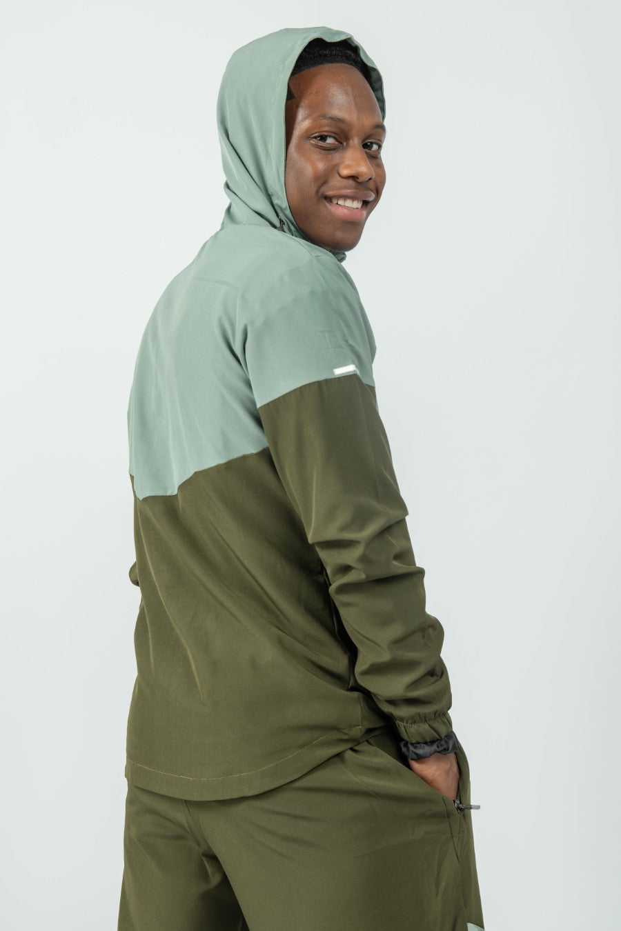 man wearing a two-tone green jacket with a hood on a white background