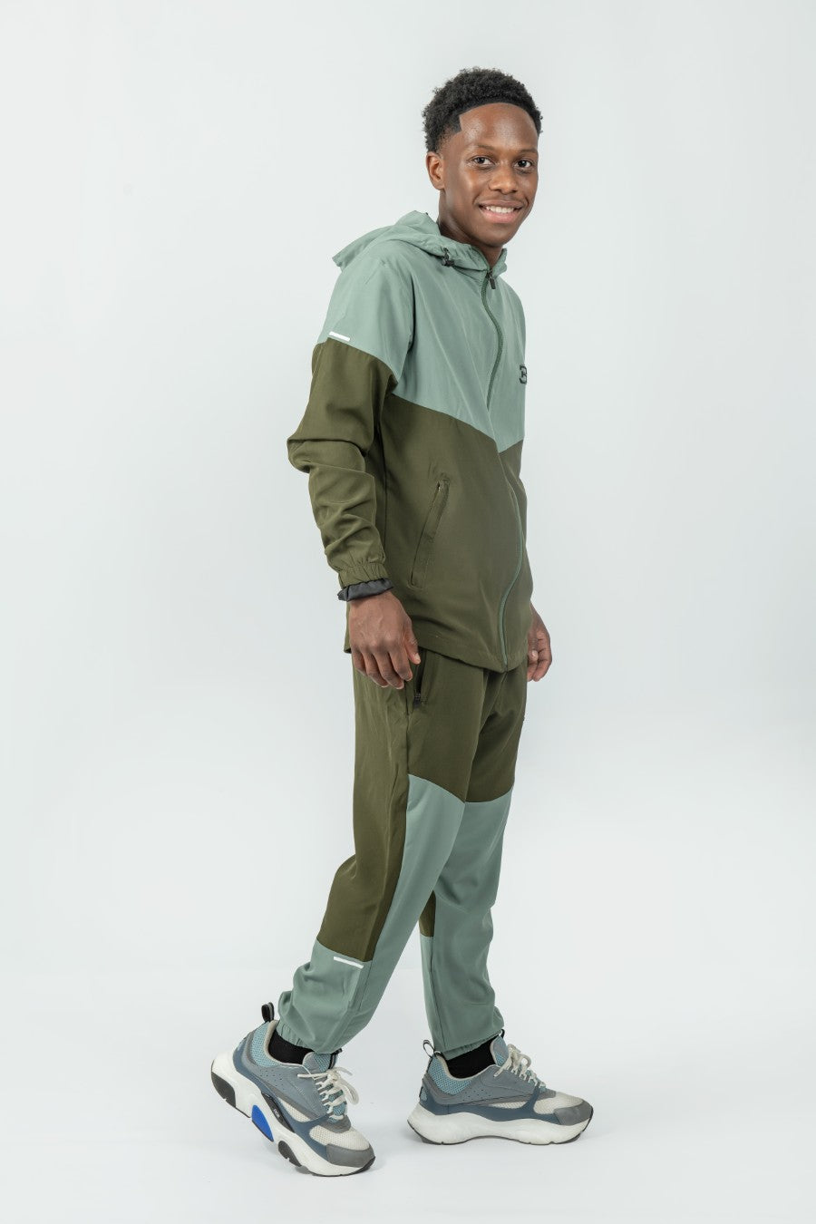 man wearing a green and dark green tracksuit set on a white background