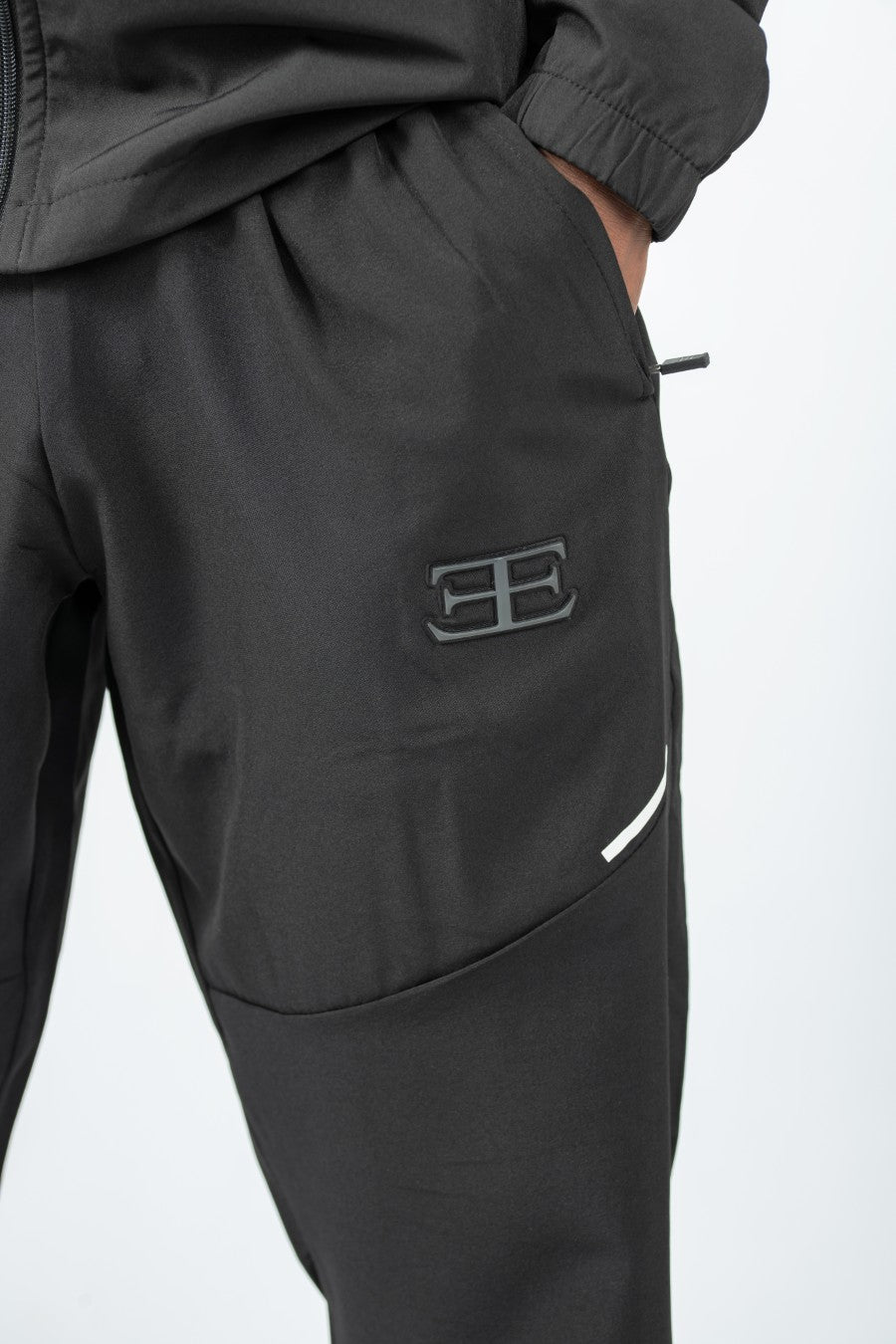 Black tracksuit pants with a logo on the pocket against a white background
