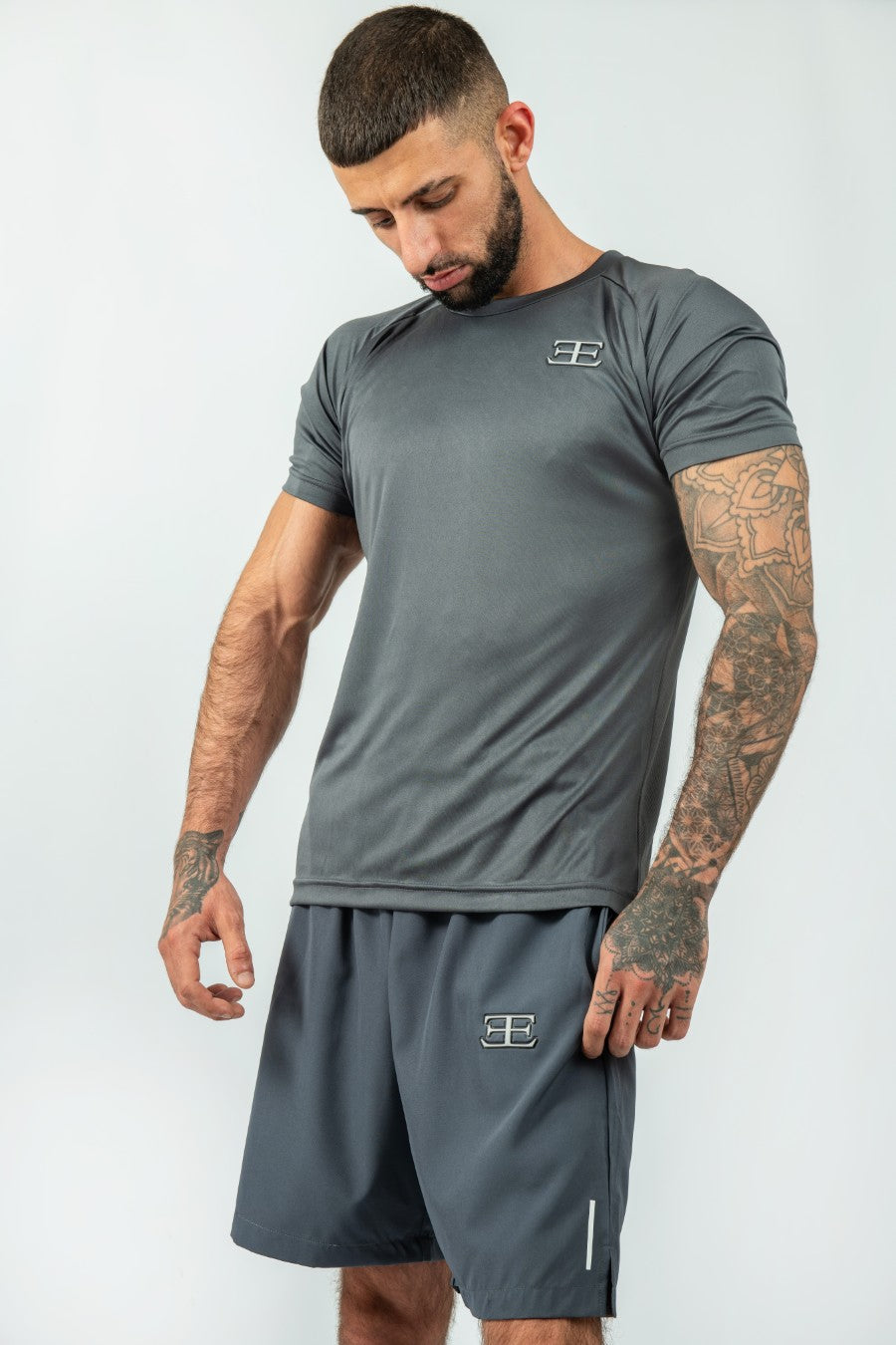 Man wearing a gray athletic outfit with a logo on a white background