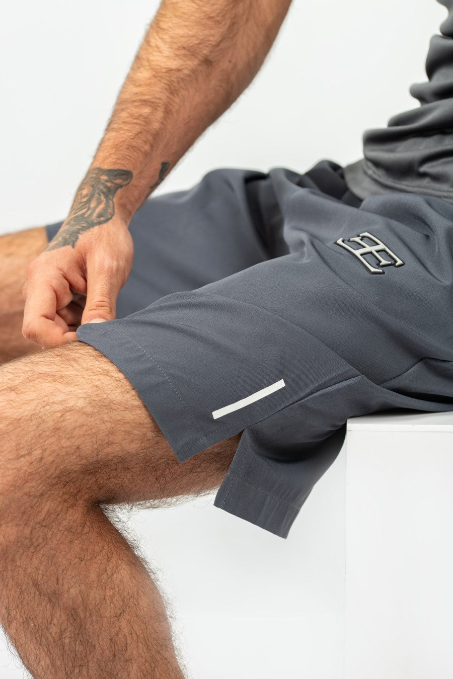 man wearing gray shorts with a brand logo on a white background