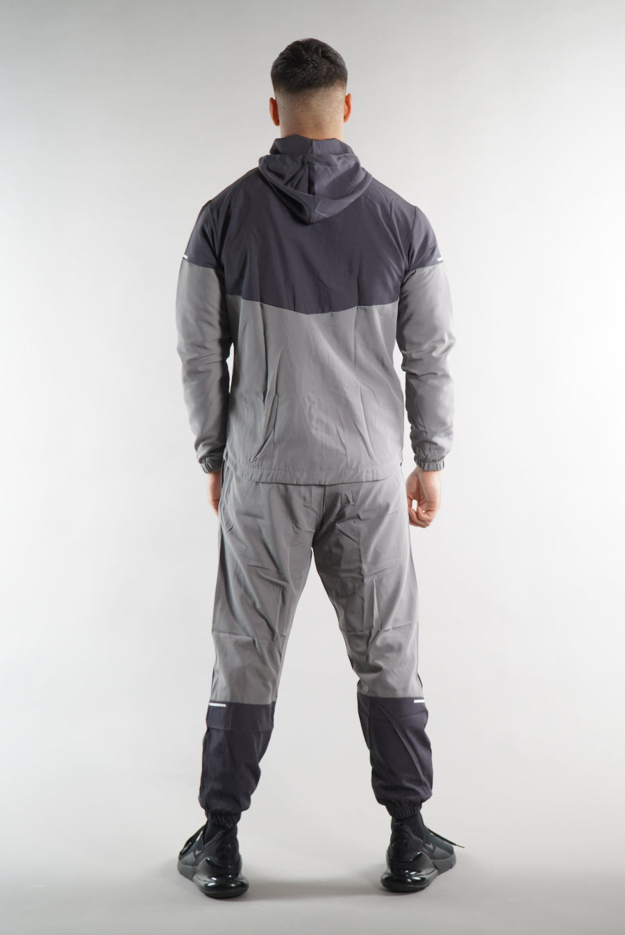 man wearing Grey Tracksuit joggers and tracksuit jacket with hood view from the. back, activewear clothing