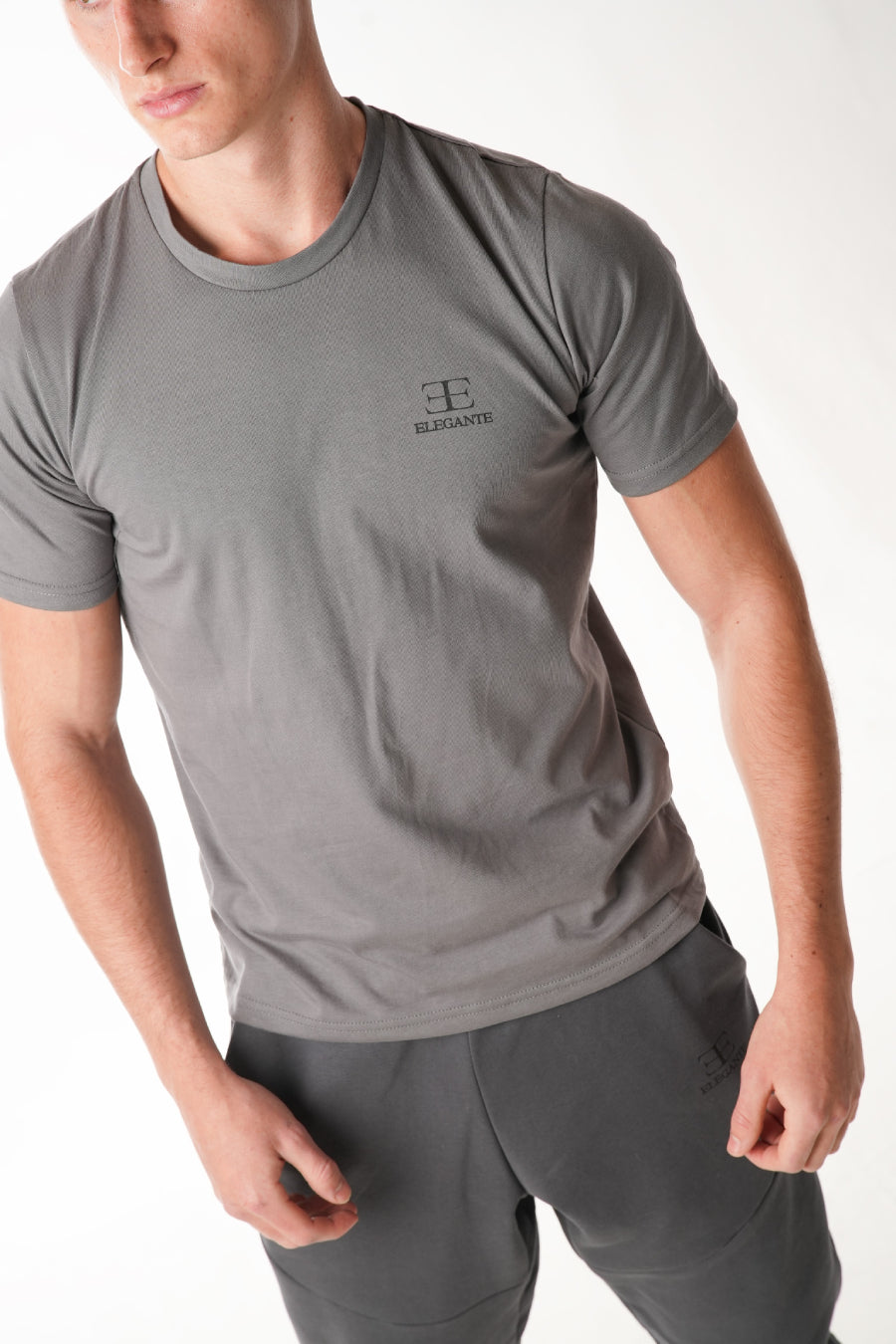 man wearing grey tshirt with elegante logo on chest on white background