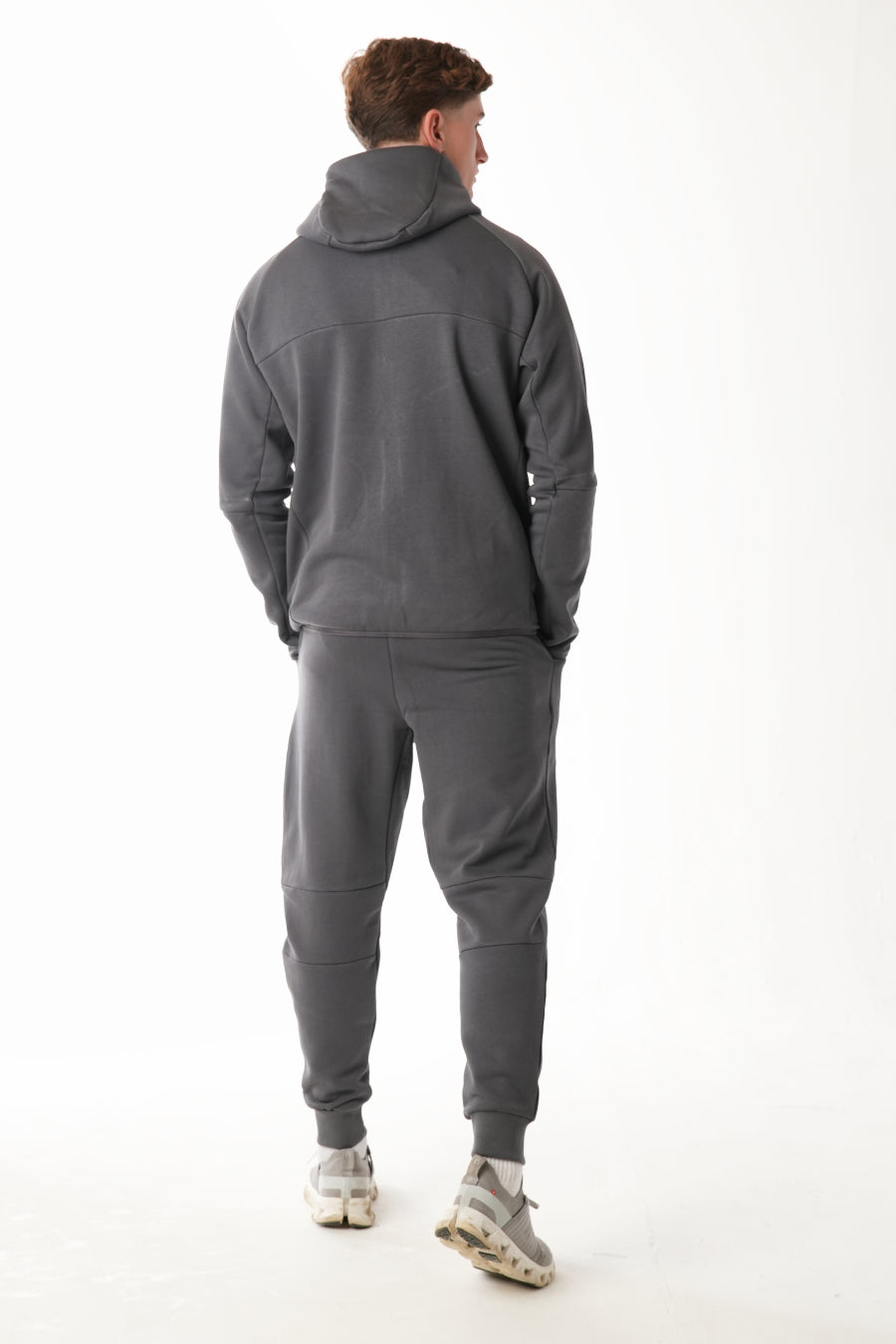 Person wearing a gray tracksuit on a white background