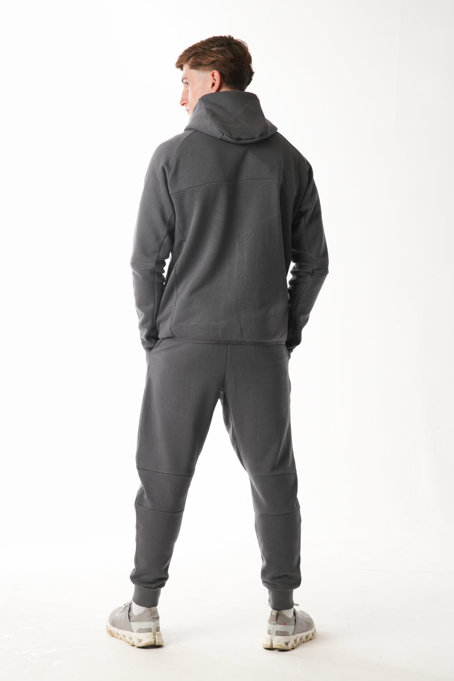Person wearing a gray tracksuit on a white background