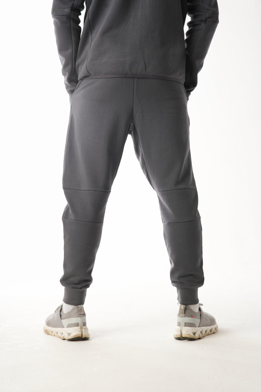 Person wearing a gray tracksuit on a white background