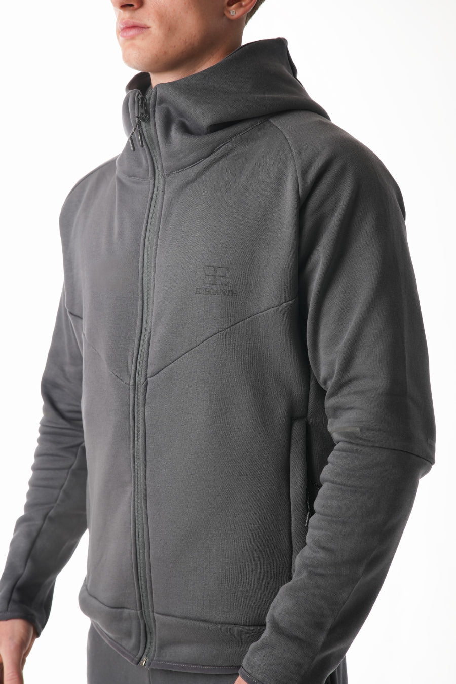 Person wearing a gray hoodie with a brand logo on a white background
