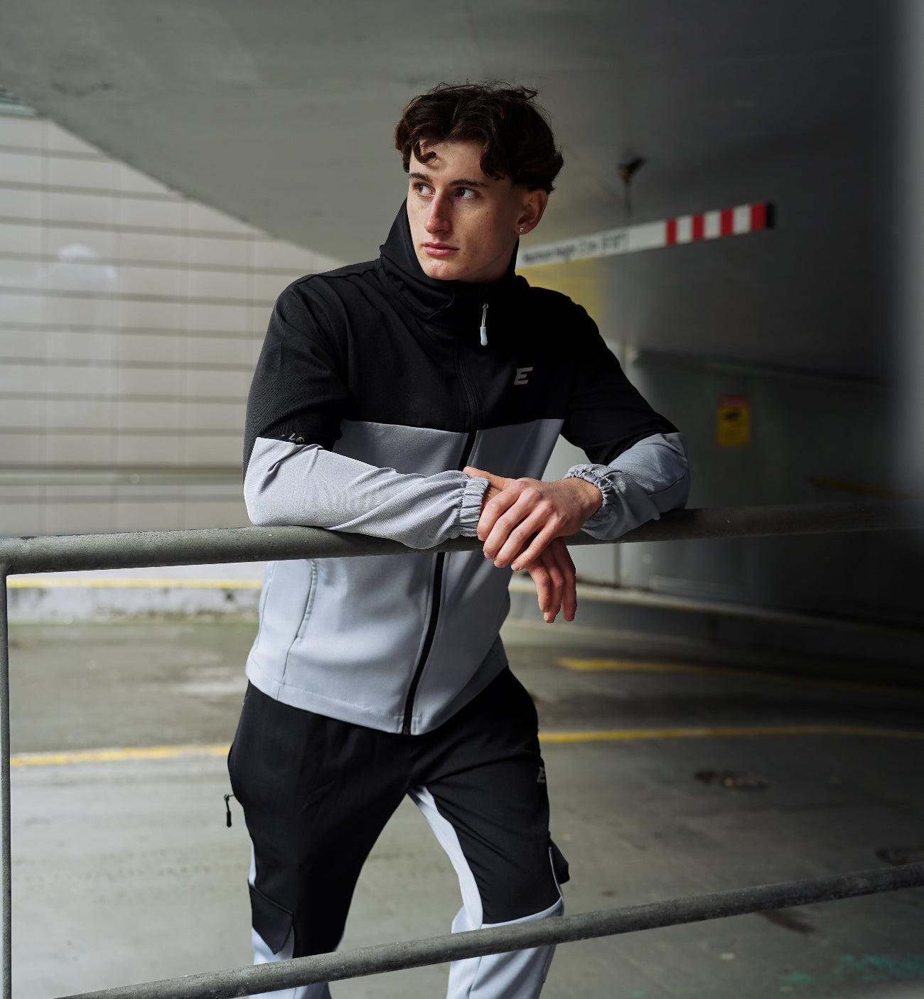 man wearing black and grey tracksuit in a car park area