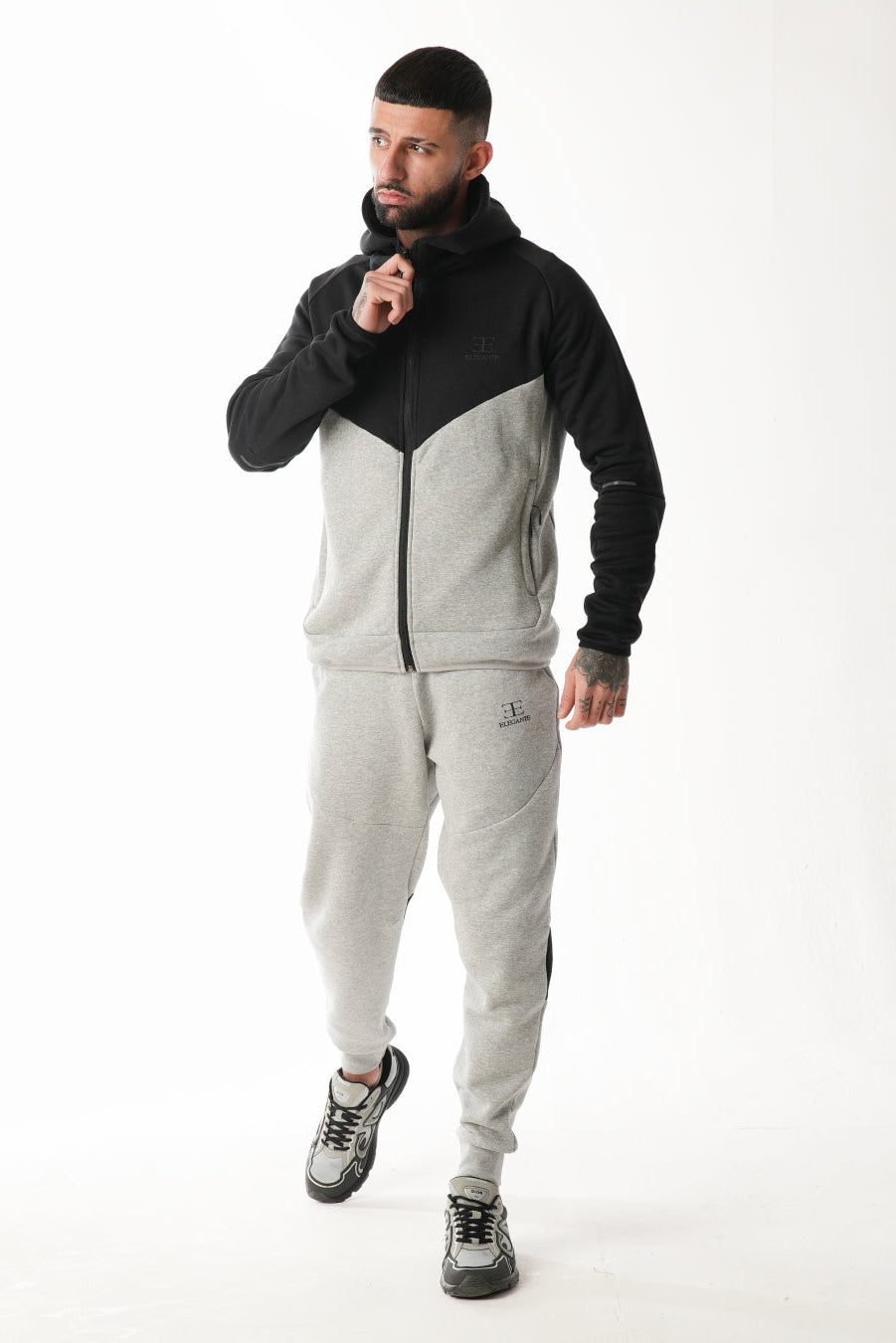 Man wearing a black and gray tracksuit on a white background