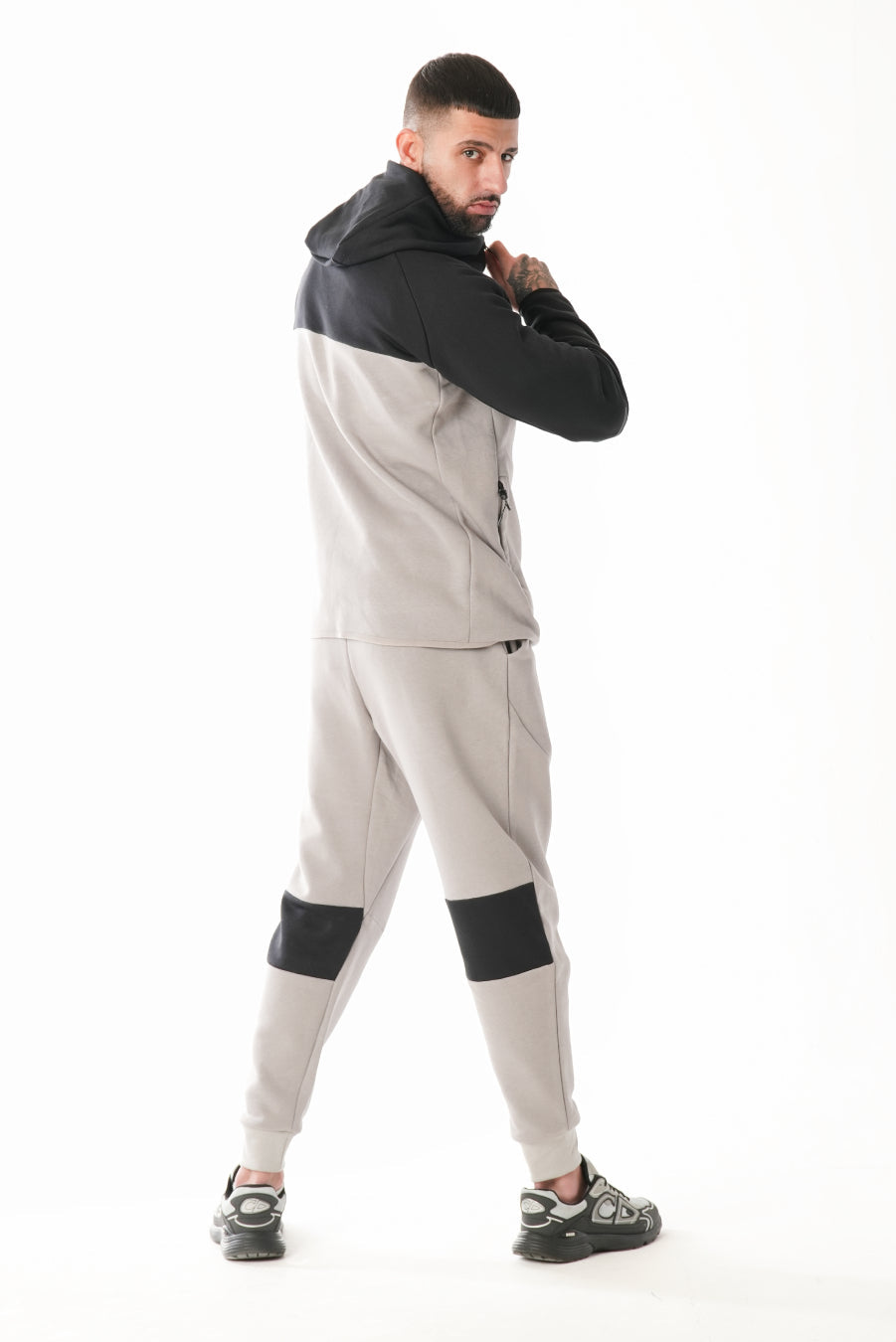 Man wearing a gray and black tracksuit on a white background
