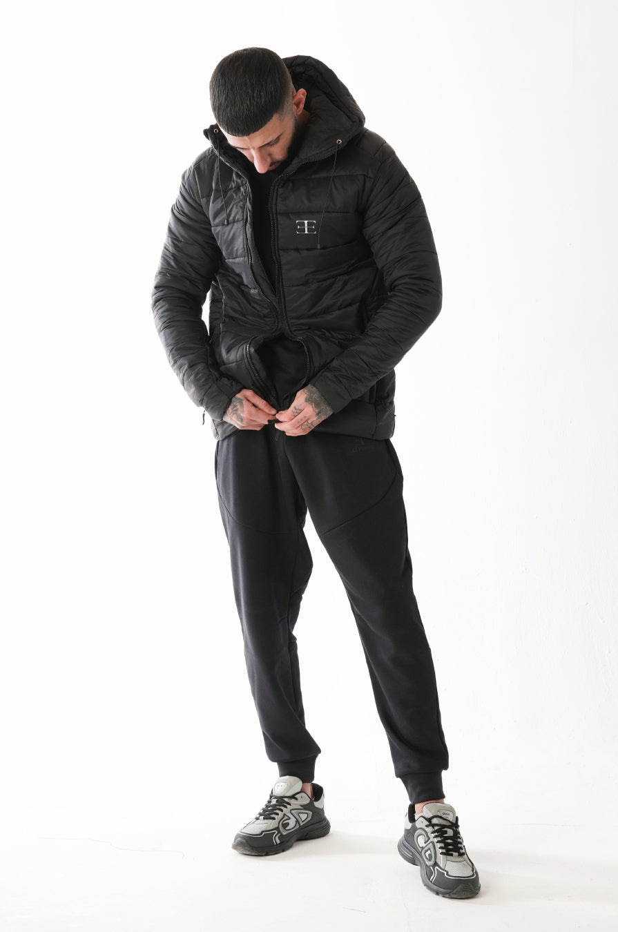 Man wearing a black puffer jacket and pants on a white background