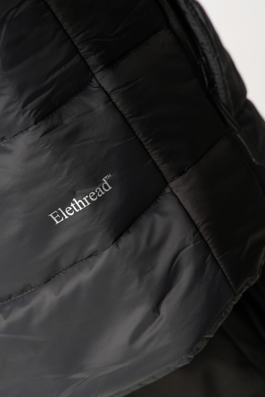 Close-up of a black jacket with 'Eilethread' branding on a white background