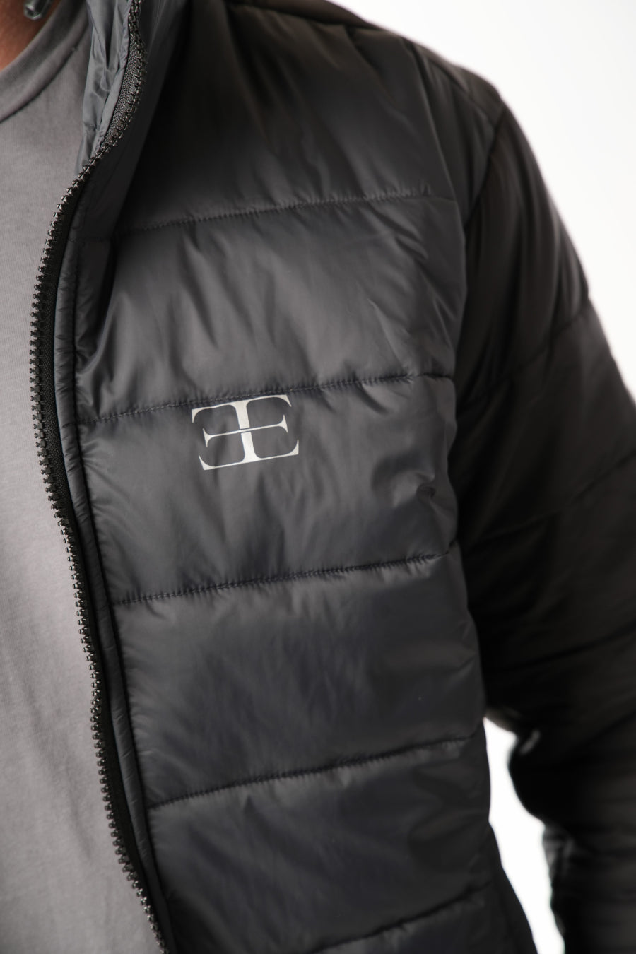 Black puffer vest with elegante brand logo on a neutral background