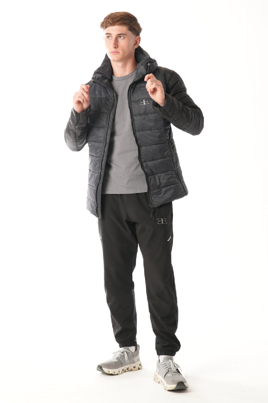 Man wearing a black puffer jacket and pants on a white background