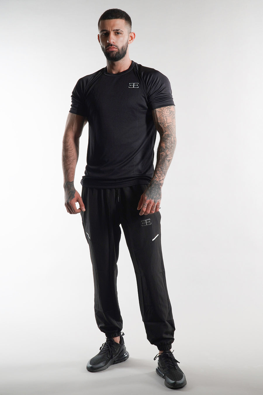 Man wearing a black t-shirt and jogger pants with elegante logo on a white background