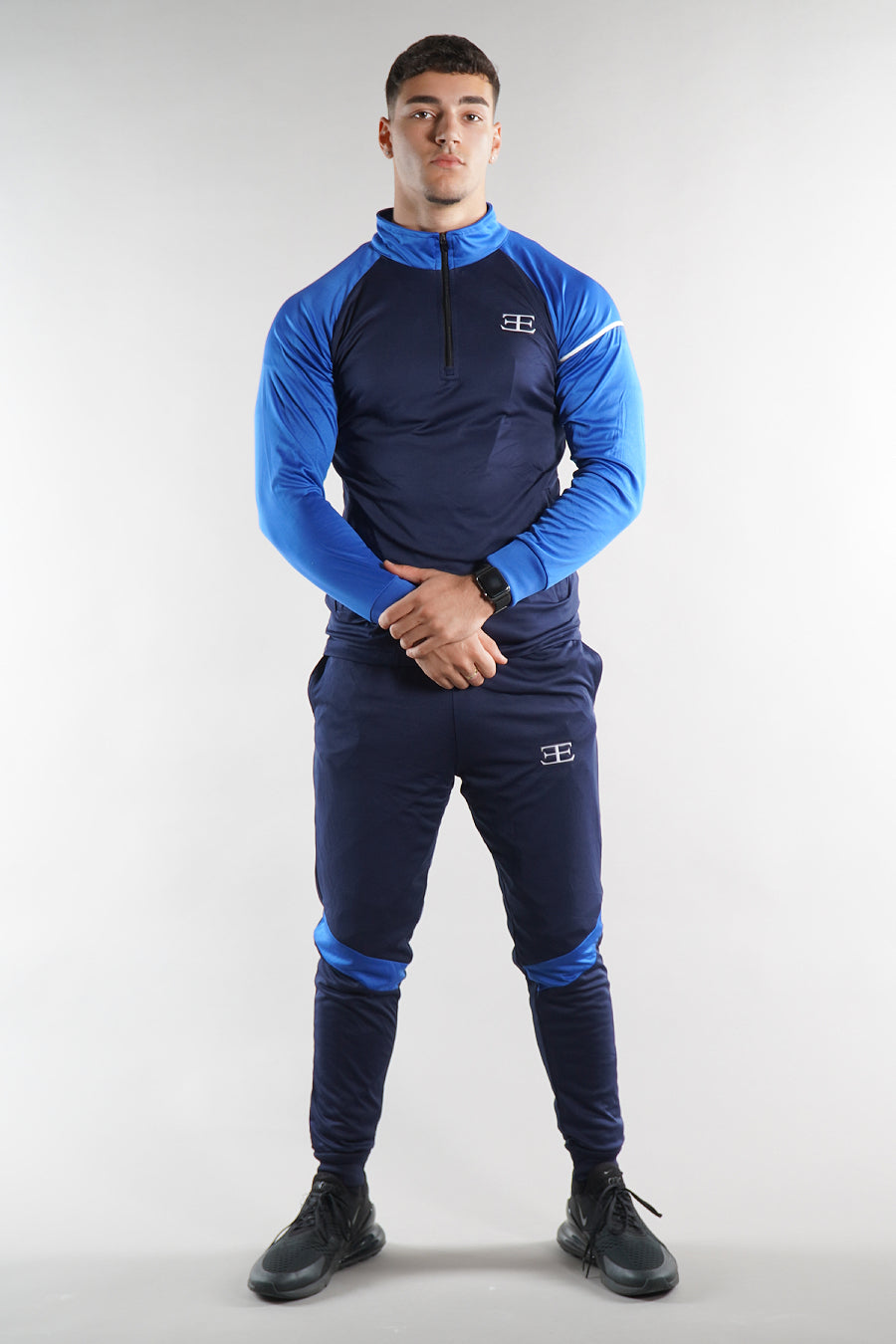 man wearing Elegante blue tracksuit zip top and joggers set white background