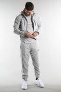 man wearing Elegante branded light grey Tracksuit jacket with hood and grey joggers on white background