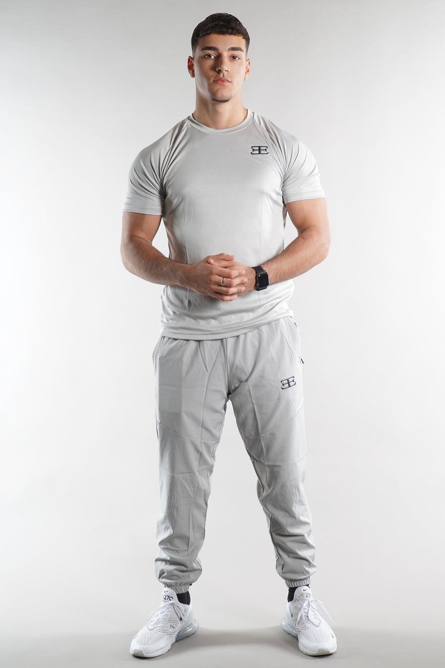 Man wearing a gray athletic outfit with a logo on a white background