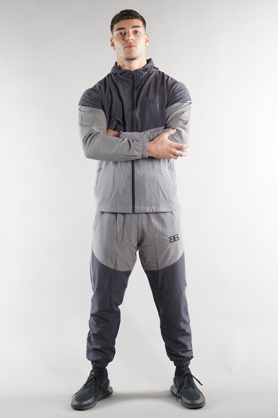man wearing grey elegante logo tracksuit jacket and joggers on white background
