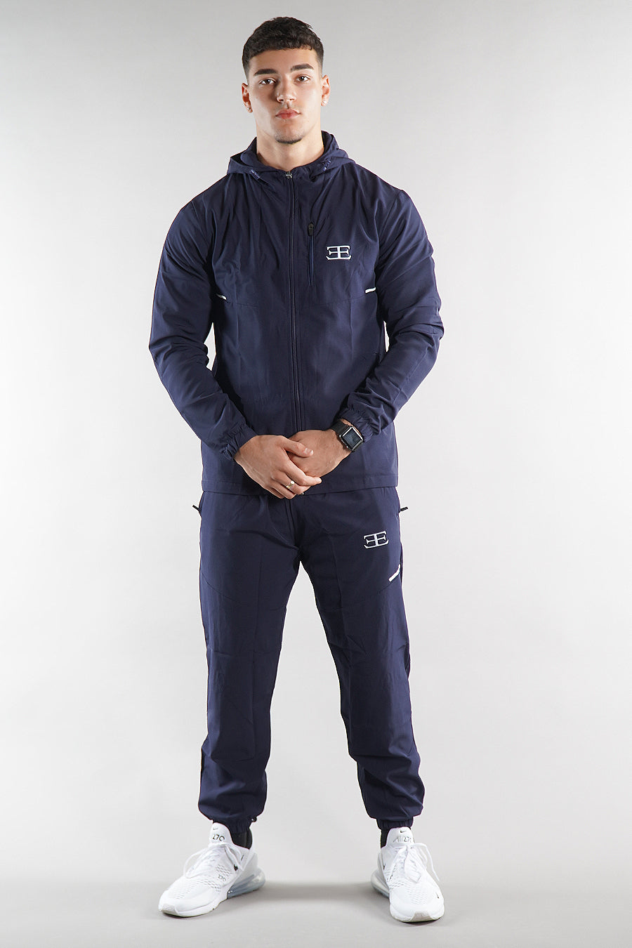 man wearing navy tracksuit jacket and joggers on white background