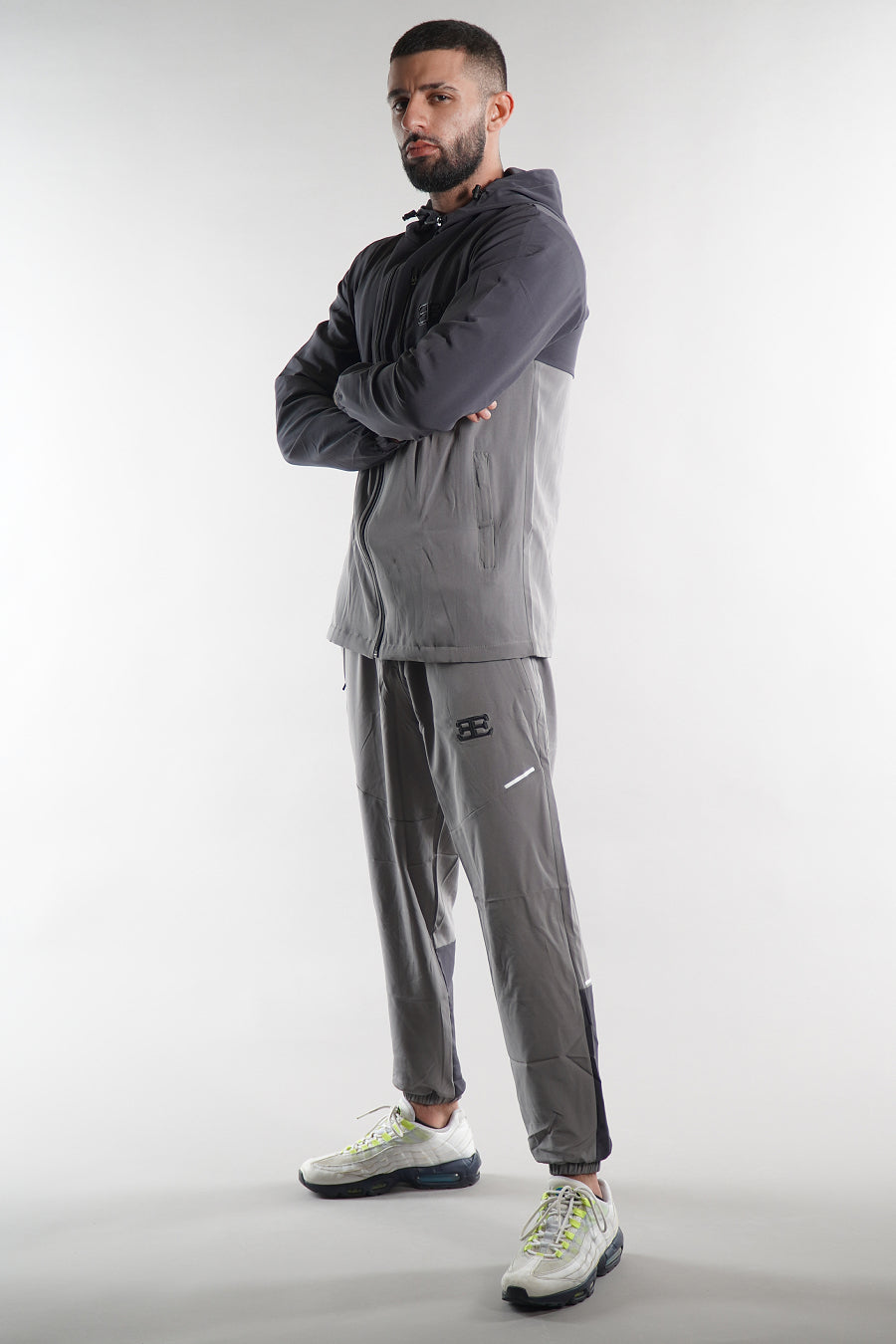 man wearing grey elegante logo tracksuit jacket and joggers on white background