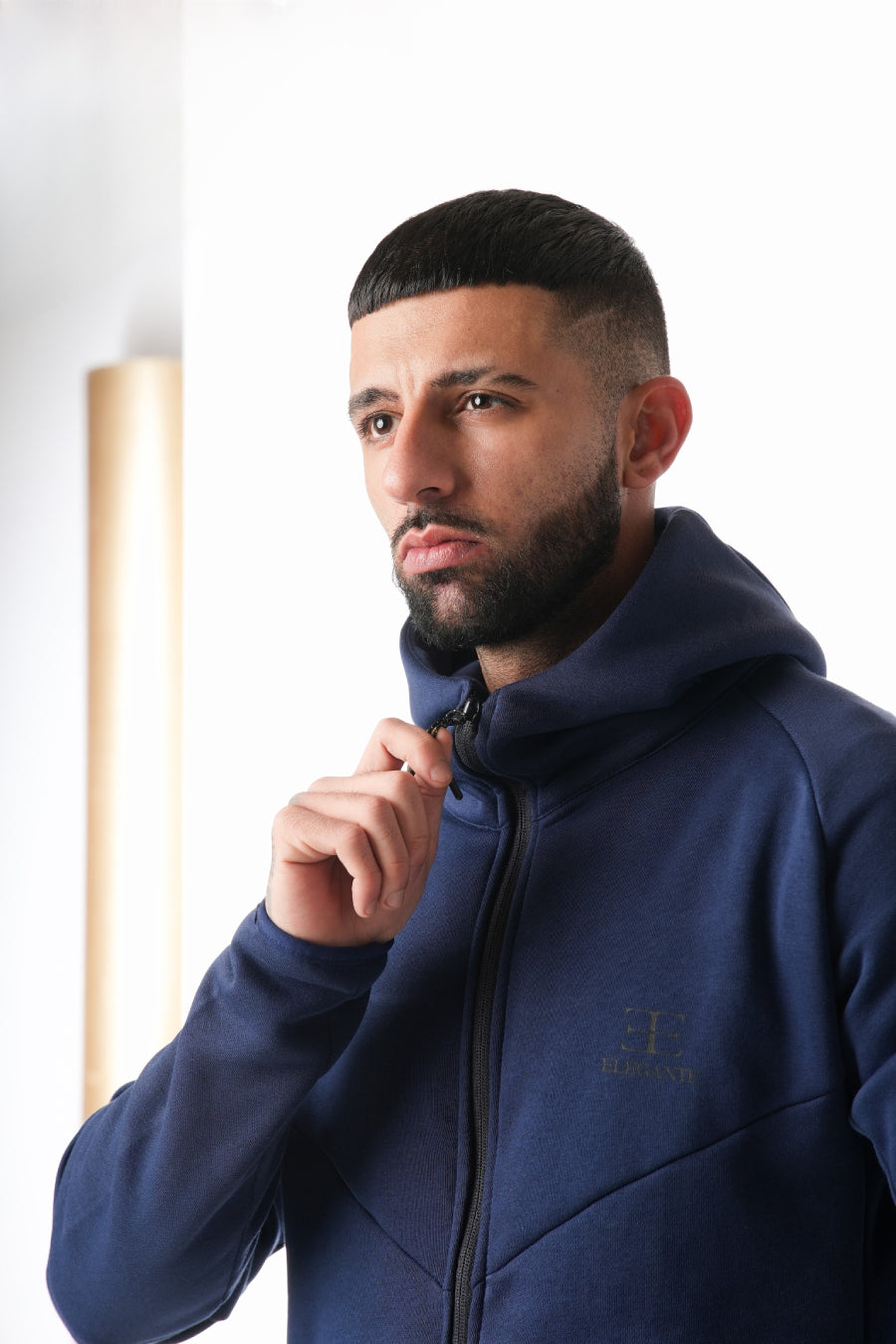 Man wearing a navy blue tracksuit hoodie on a white background