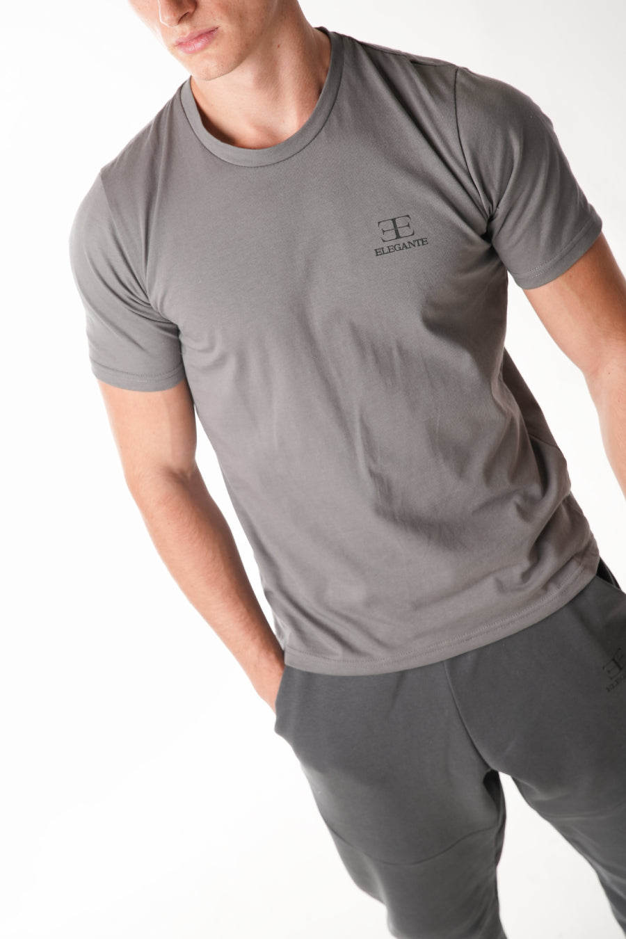 man wearing grey tshirt with elegante logo on chest on white background