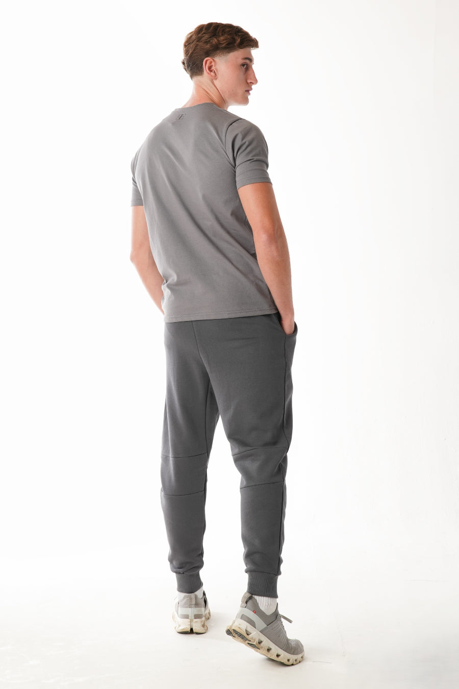 Man wearing a gray t-shirt and jogger pants on a white background