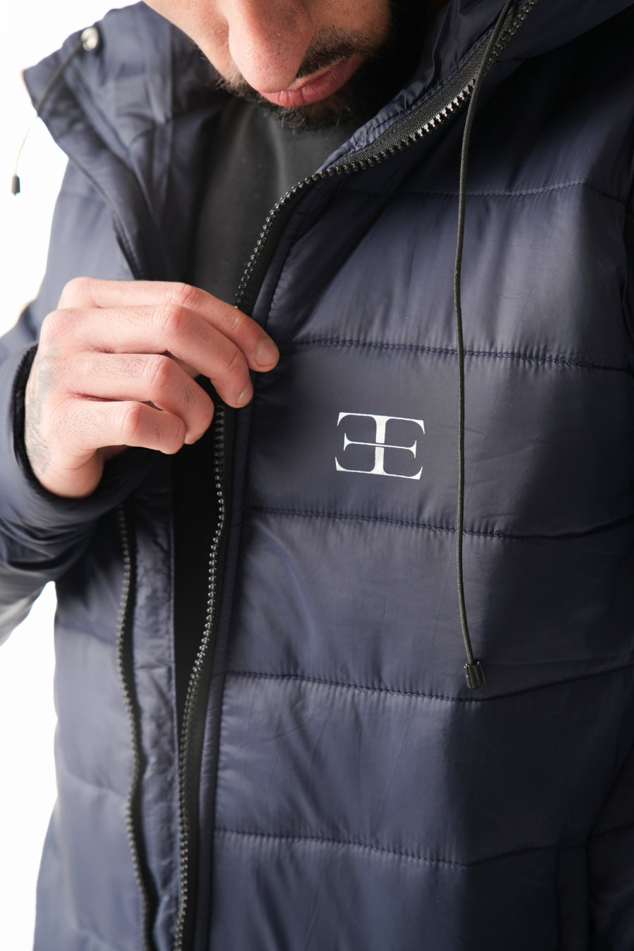 Person wearing a dark blue puffer jacket with a brand logo on the chest.