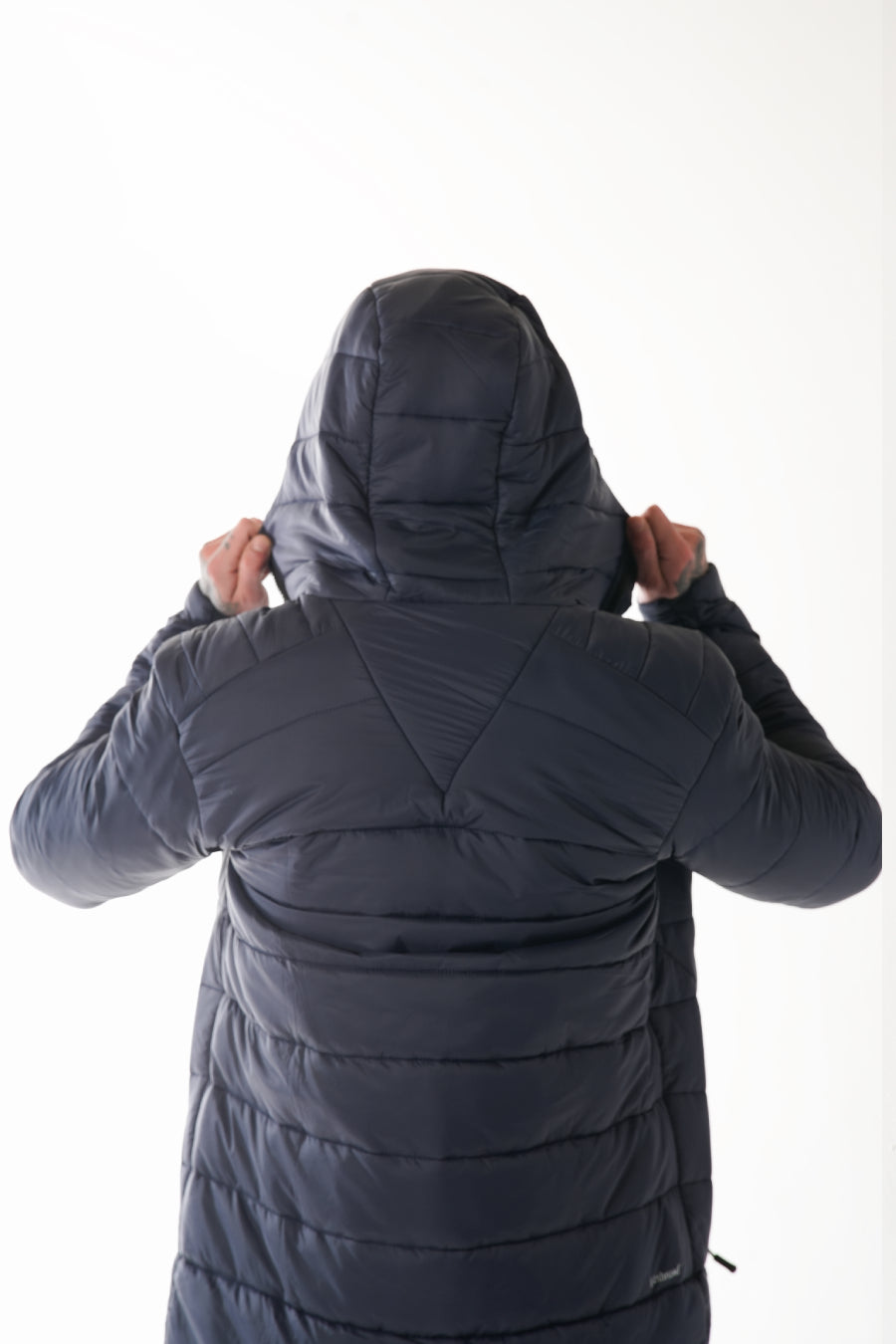 Person wearing a dark navy puffer jacket with the hood up on a white background