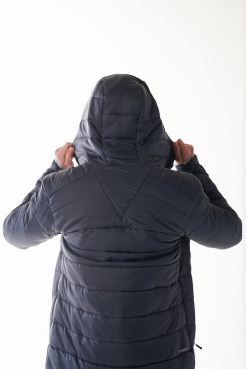 Person wearing a dark navy puffer jacket with the hood up on a white background