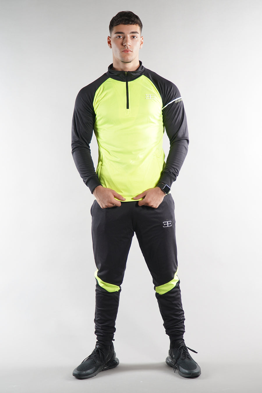 man wearing Elegante neon green tracksuit top and joggers, sportswear set on white background