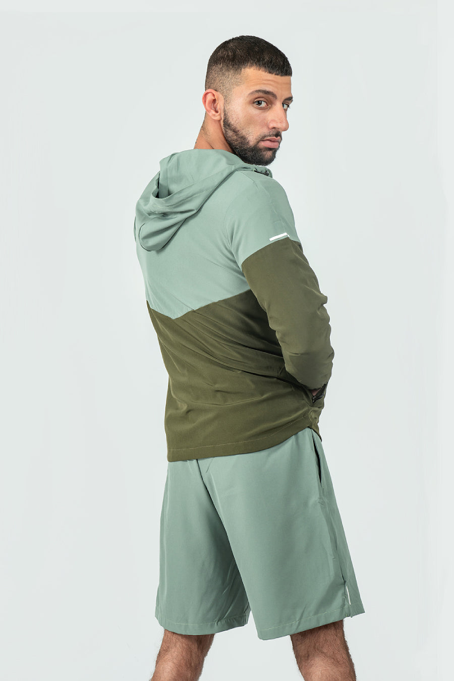 Man wearing a green and olive tracksuit with a logo on a white background