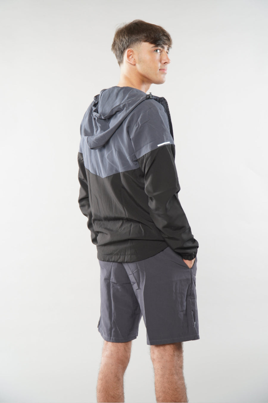 Man wearing a grey tracksuit jacket with shorts with elegante logo on a white background